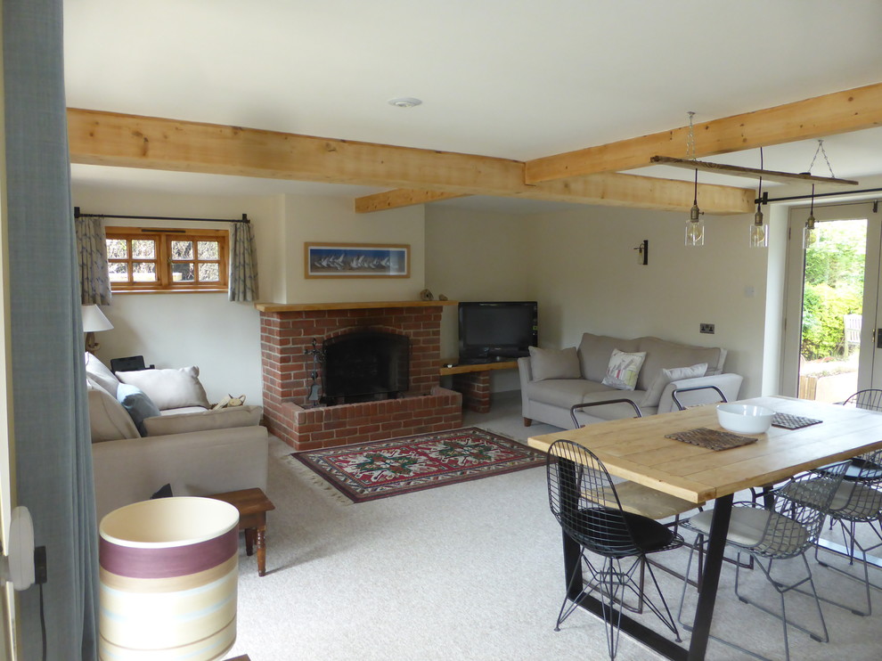 Photo of a medium sized coastal open plan living room with carpet, a standard fireplace, a brick fireplace surround and a freestanding tv.