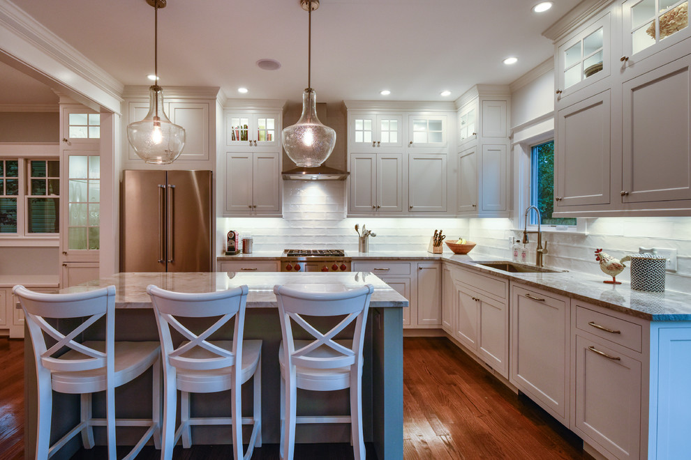 Design ideas for a mid-sized country l-shaped eat-in kitchen in DC Metro with an undermount sink, beaded inset cabinets, white cabinets, quartzite benchtops, white splashback, porcelain splashback, stainless steel appliances, medium hardwood floors and with island.