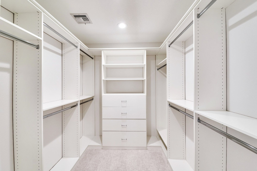 Immagine di una cabina armadio unisex tradizionale di medie dimensioni con ante lisce, ante bianche, moquette e pavimento beige