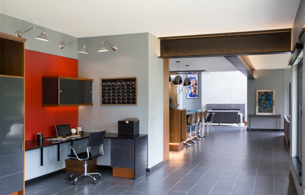 This is an example of a modern home studio in Cedar Rapids with multi-coloured walls, a built-in desk, grey floor and slate floors.