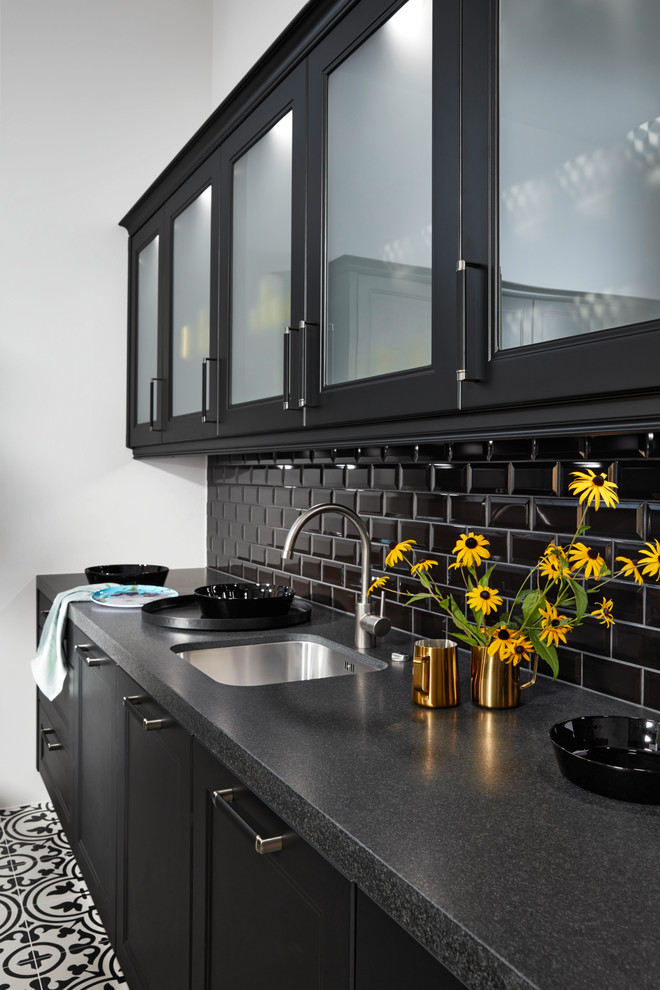 Large transitional eat-in kitchen in Paris with an integrated sink, glass-front cabinets, black cabinets, laminate benchtops, black splashback, subway tile splashback, black appliances, cement tiles and with island.