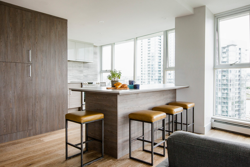 Design ideas for a contemporary open plan kitchen in Vancouver with flat-panel cabinets, white cabinets, grey splashback, stainless steel appliances, medium hardwood floors, a peninsula and brown floor.