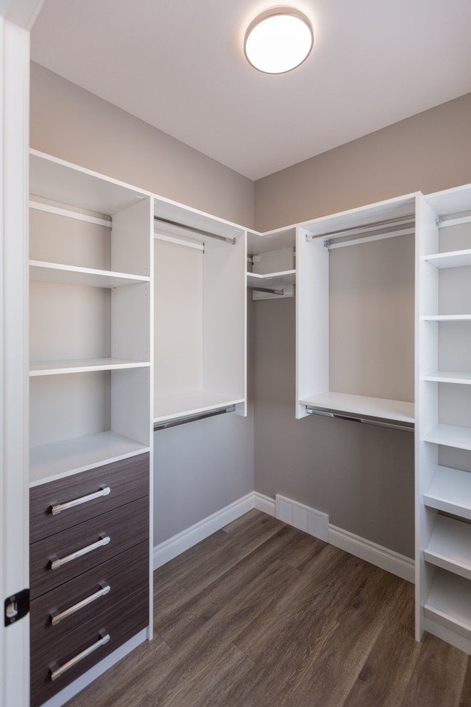 Small transitional gender-neutral walk-in wardrobe in Edmonton with flat-panel cabinets, medium wood cabinets and laminate floors.