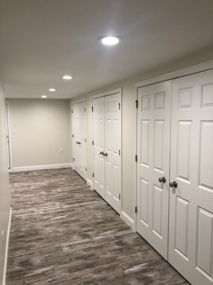 This is an example of a large modern basement in Boston with laminate floors and grey floor.