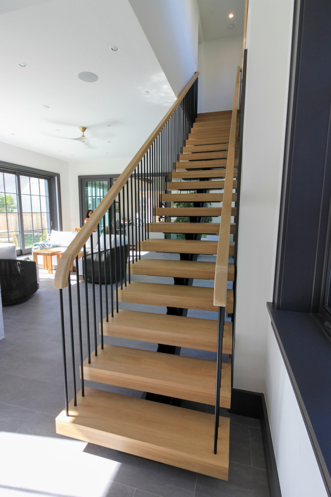 Пример оригинального дизайна: огромная лестница на больцах в стиле модернизм с деревянными ступенями, перилами из смешанных материалов и стенами из вагонки