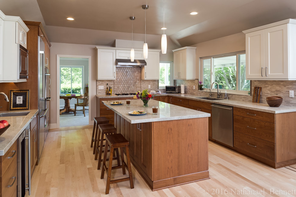 Mid-sized transitional u-shaped eat-in kitchen in San Francisco with an undermount sink, shaker cabinets, white cabinets, beige splashback, matchstick tile splashback, stainless steel appliances, light hardwood floors and with island.