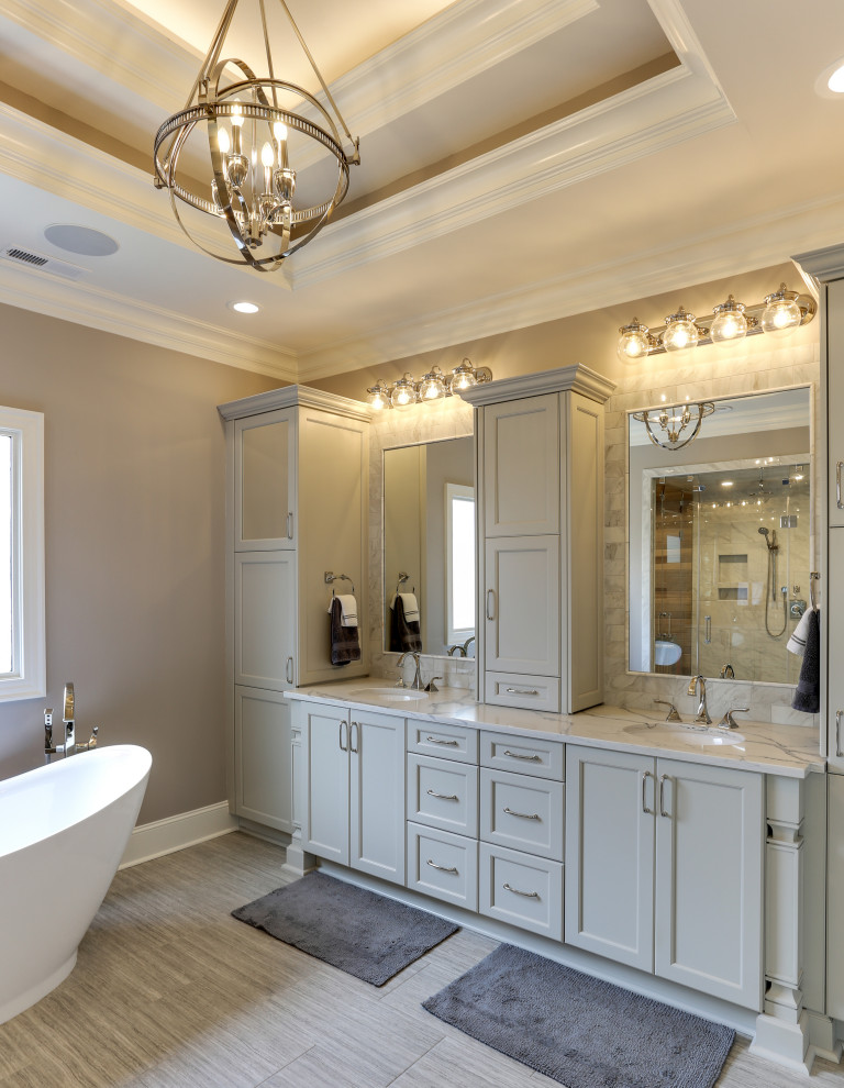Traditional master wet room bathroom in Raleigh with recessed-panel cabinets, grey cabinets, a freestanding tub, beige walls, an undermount sink, engineered quartz benchtops, brown floor, a hinged shower door, multi-coloured benchtops, a double vanity, a built-in vanity and recessed.