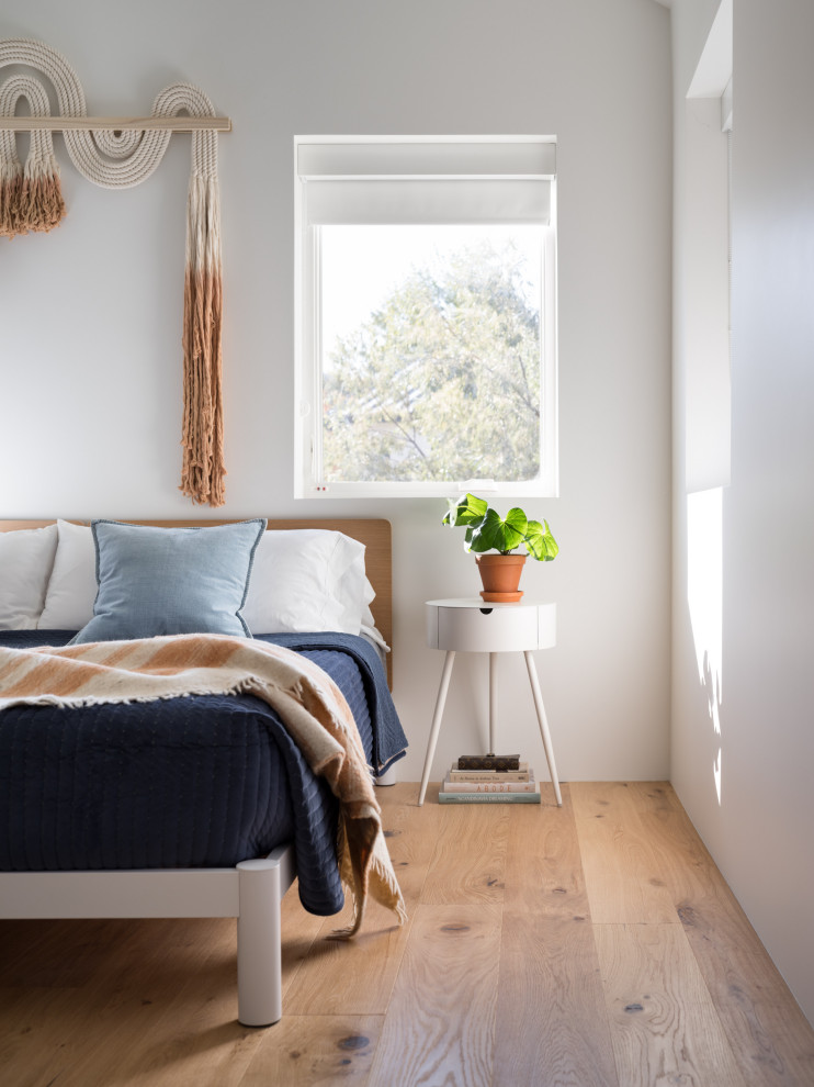Scandinavian bedroom in Los Angeles with white walls, medium hardwood flooring and brown floors.
