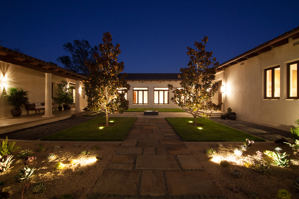 Design ideas for a large transitional backyard patio in Santa Barbara with natural stone pavers and a roof extension.