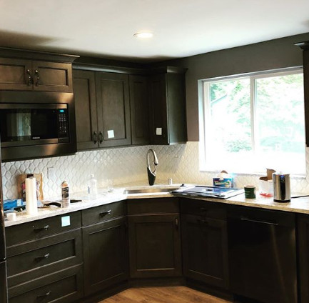Inspiration for a mid-sized transitional light wood floor and brown floor kitchen remodel in Seattle with an undermount sink, flat-panel cabinets, brown cabinets, quartz countertops, white backsplash, mosaic tile backsplash, stainless steel appliances and white countertops