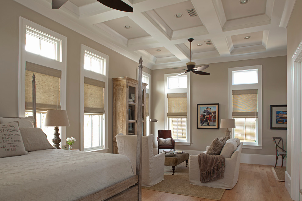 This is an example of a beach style bedroom in Miami with beige walls and light hardwood floors.