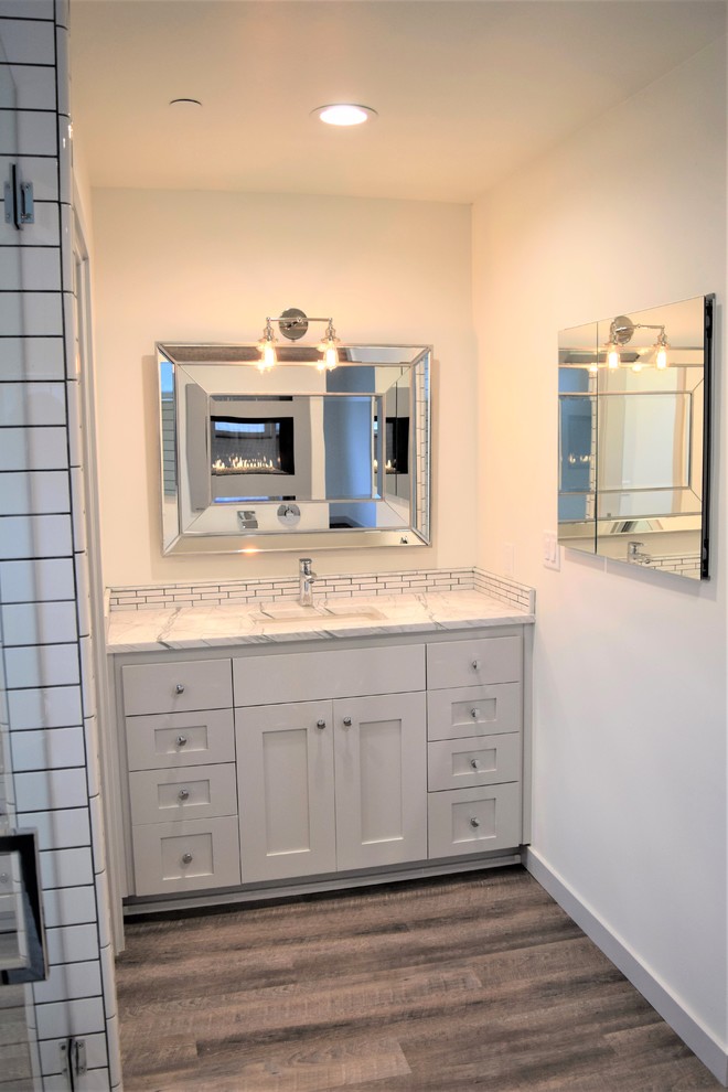 Design ideas for a mid-sized modern master bathroom in San Luis Obispo with shaker cabinets, grey cabinets, a freestanding tub, a corner shower, a one-piece toilet, white tile, ceramic tile, white walls, linoleum floors, an undermount sink, marble benchtops, brown floor and a hinged shower door.