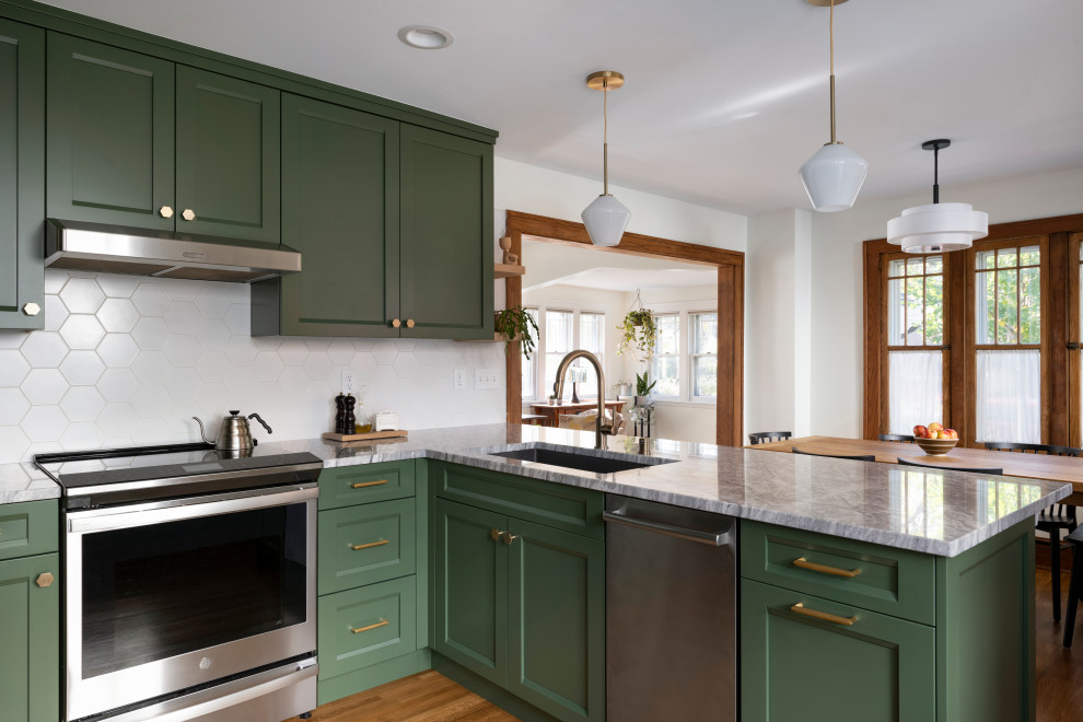 Design ideas for a transitional kitchen in Minneapolis with an undermount sink, recessed-panel cabinets, green cabinets, granite benchtops, white splashback, ceramic splashback, stainless steel appliances, light hardwood floors, brown floor and white benchtop.