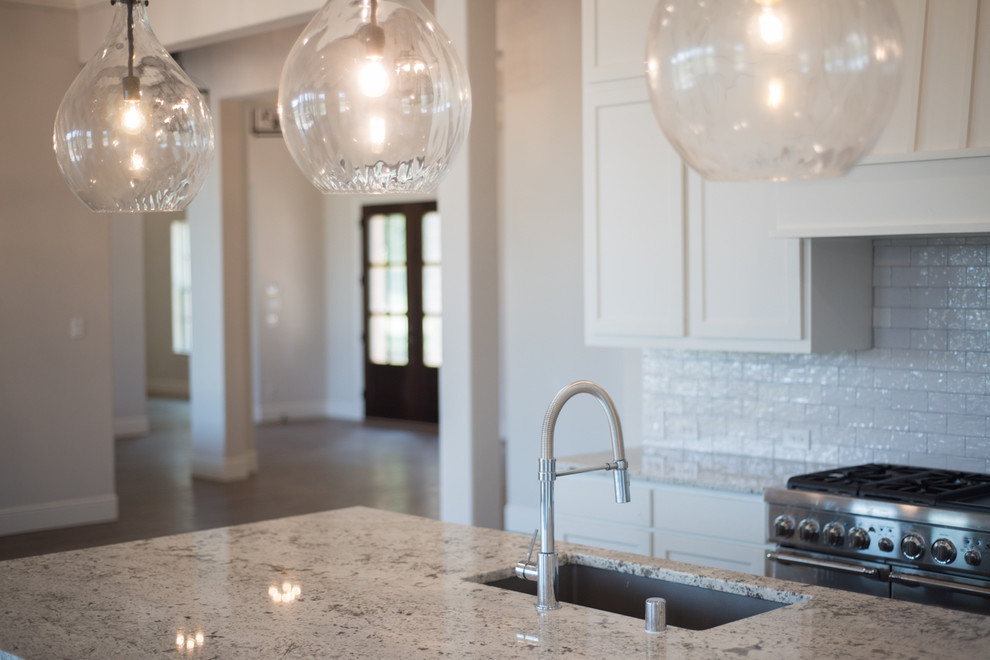 Eat-in kitchen - large transitional u-shaped medium tone wood floor and brown floor eat-in kitchen idea in Dallas with a drop-in sink, recessed-panel cabinets, white cabinets, granite countertops, white backsplash, ceramic backsplash, stainless steel appliances, an island and gray countertops
