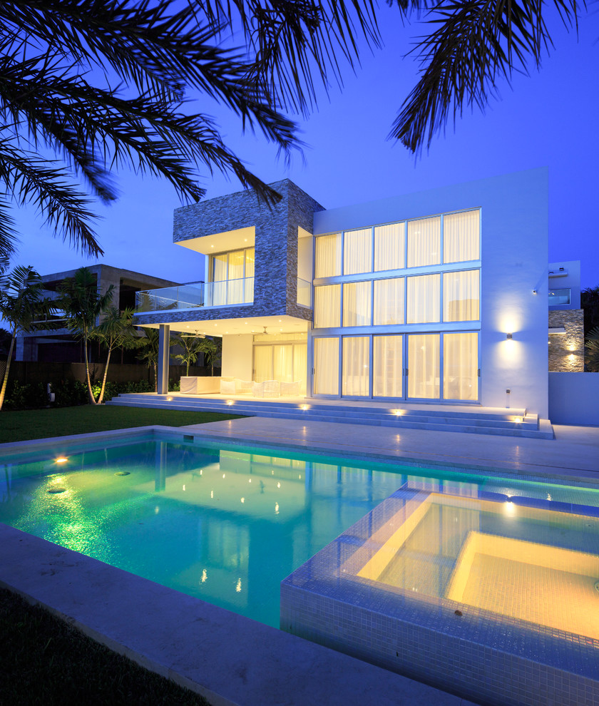 Inspiration for an expansive contemporary backyard rectangular infinity pool in Miami with a hot tub and concrete slab.