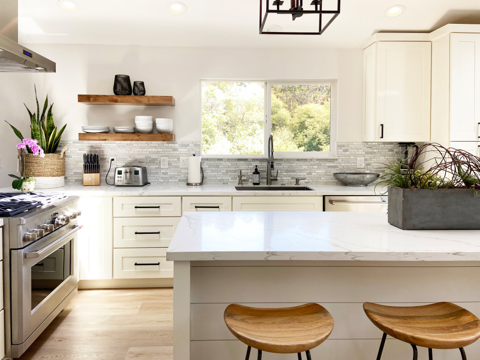 Kitchen - mid-sized transitional l-shaped vinyl floor, brown floor and vaulted ceiling kitchen idea with an undermount sink, shaker cabinets, white cabinets, quartz countertops, multicolored backsplash, mosaic tile backsplash, stainless steel appliances, an island and white countertops