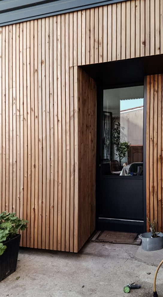 Photo of a medium sized and black contemporary two floor terraced house in Nantes with wood cladding, a butterfly roof, a tiled roof, a red roof and shiplap cladding.