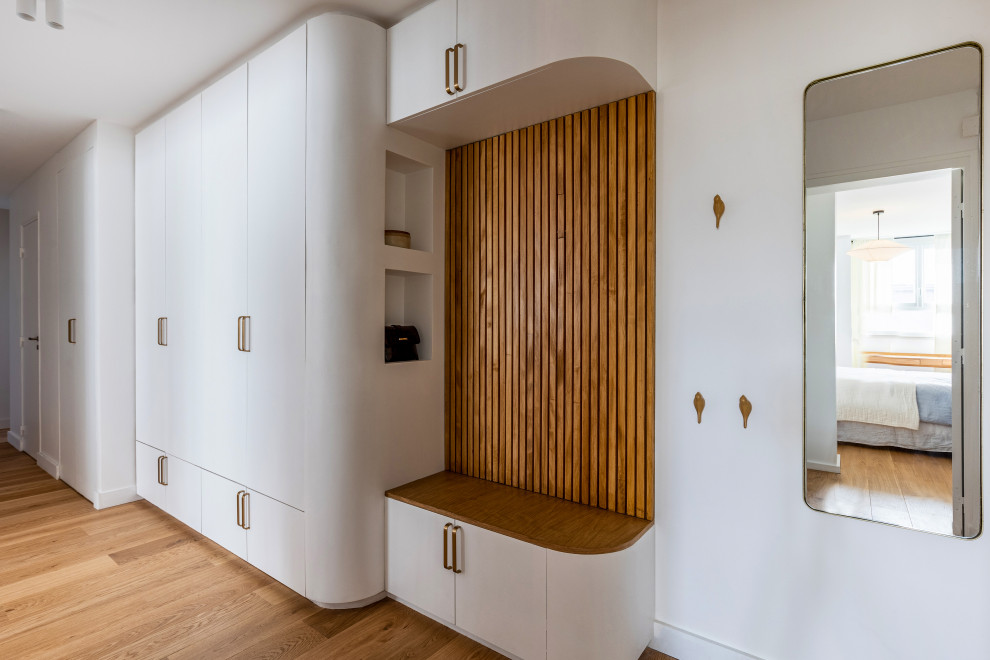 Diseño de hall vintage de tamaño medio con paredes blancas, suelo de madera clara, puerta blanca y suelo marrón