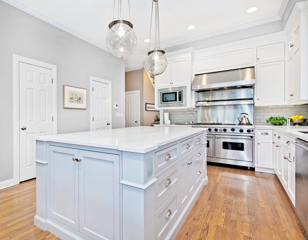 Inspiration for a mid-sized transitional l-shaped light wood floor and beige floor kitchen remodel in Chicago with an undermount sink, shaker cabinets, white cabinets, quartzite countertops, gray backsplash, subway tile backsplash, stainless steel appliances and an island