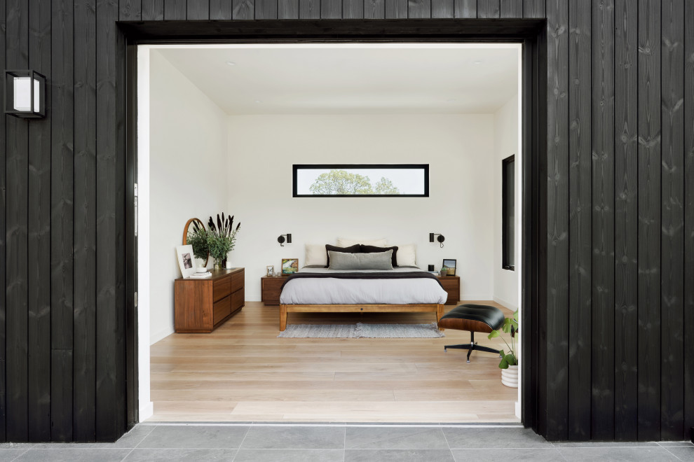 Inspiration för mellanstora moderna huvudsovrum, med vita väggar, mellanmörkt trägolv och brunt golv