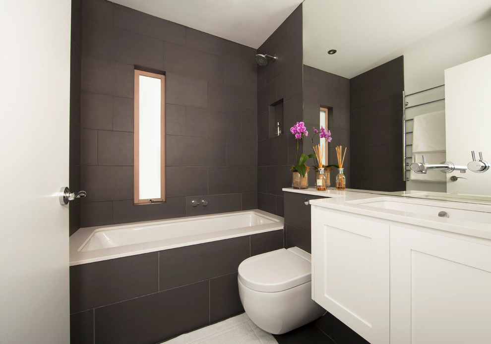 Design ideas for a mid-sized contemporary bathroom in Sydney with an undermount sink, recessed-panel cabinets, white cabinets, an undermount tub, a shower/bathtub combo, a wall-mount toilet, black tile, white walls, porcelain floors, ceramic tile and an open shower.