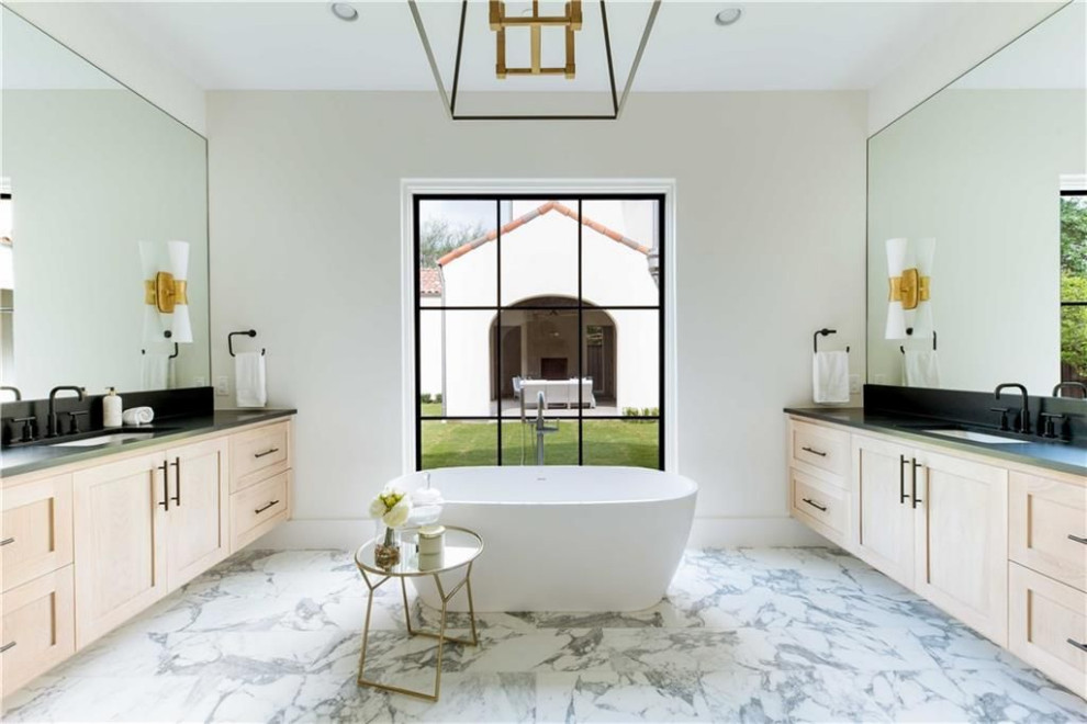 Large transitional master bathroom in Dallas with recessed-panel cabinets, light wood cabinets, a freestanding tub, white tile, white walls, marble floors, an undermount sink, white floor and black benchtops.