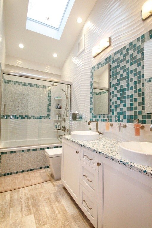 Design ideas for a small contemporary kids bathroom in New York with an undermount sink, white cabinets, a wall-mount toilet, green tile, glass tile and white walls.