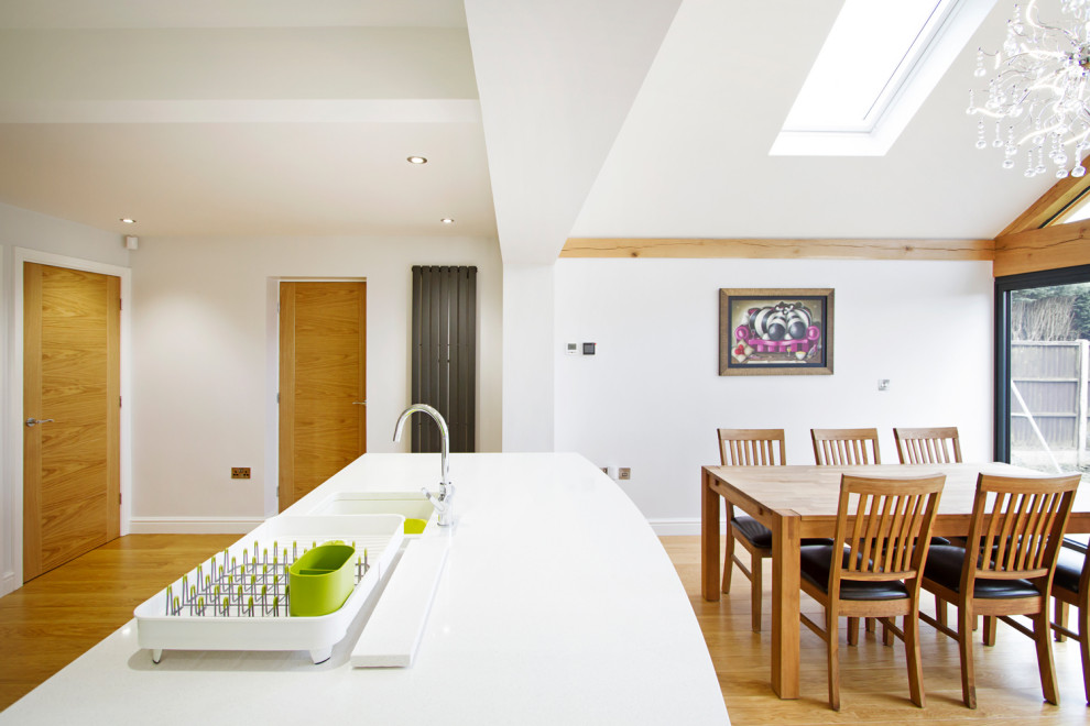 This is an example of a small contemporary l-shaped open plan kitchen in West Midlands with a drop-in sink, flat-panel cabinets, grey cabinets, granite benchtops, green splashback, glass sheet splashback, stainless steel appliances, laminate floors, with island, beige floor, white benchtop and vaulted.