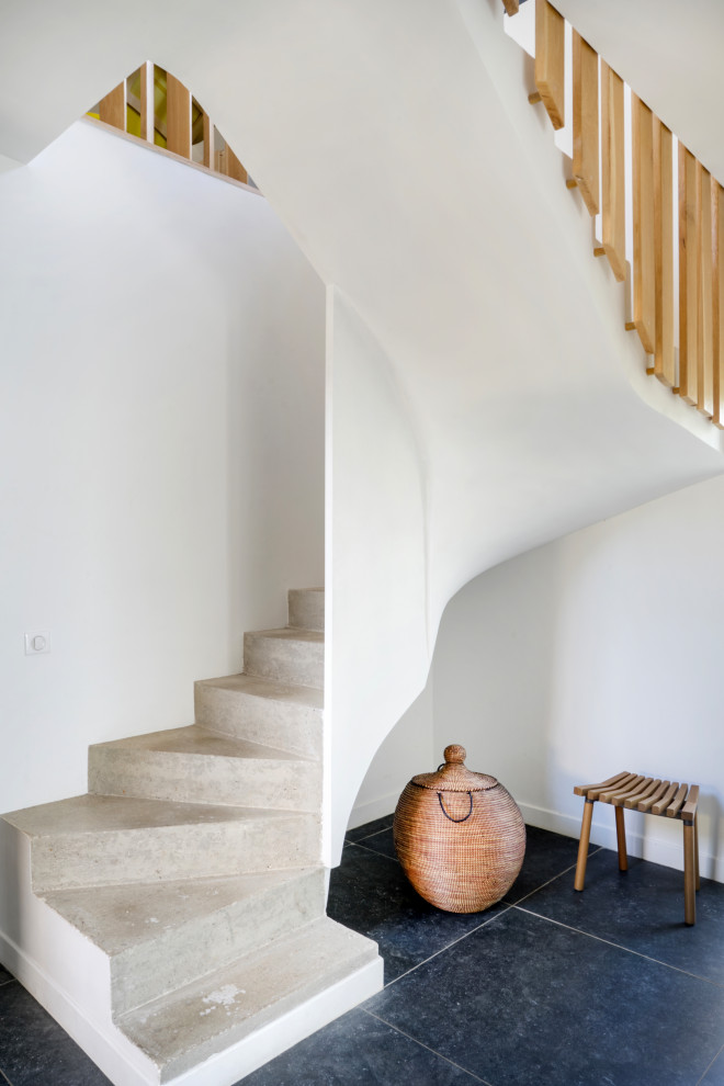 Пример оригинального дизайна: изогнутая бетонная лестница в современном стиле с бетонными ступенями и деревянными перилами