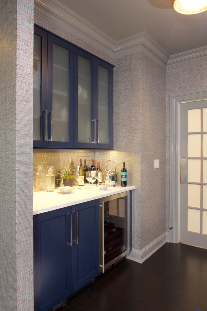 This is an example of a small traditional single-wall wet bar in New York with glass-front cabinets, blue cabinets, quartzite benchtops, dark hardwood floors and brown floor.