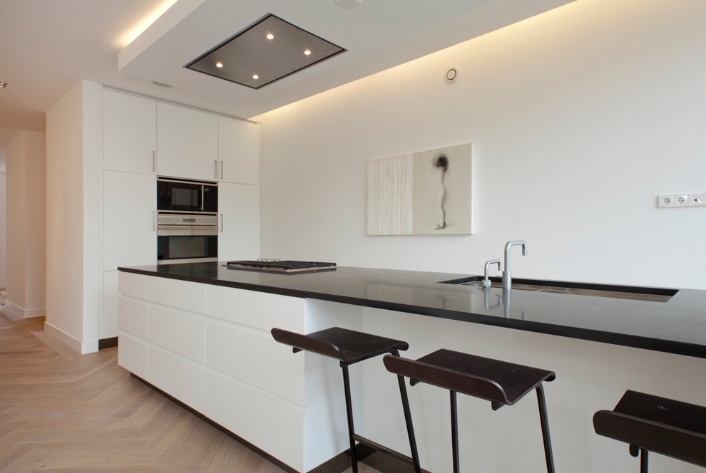 This is an example of a contemporary kitchen in Amsterdam with flat-panel cabinets and black benchtop.