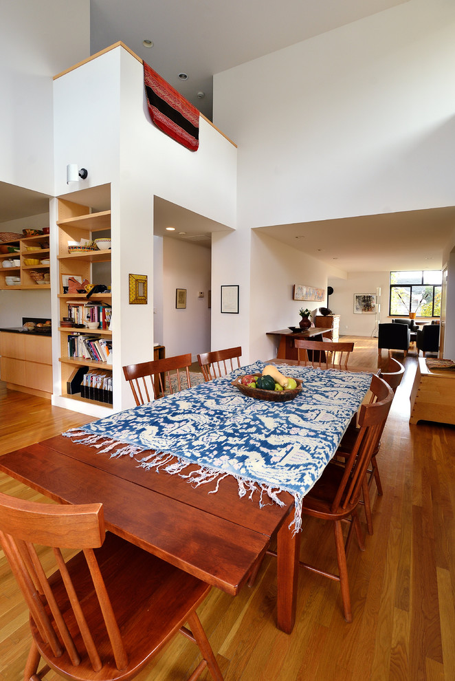 Large modern open plan dining in Seattle with white walls, dark hardwood floors, no fireplace and brown floor.