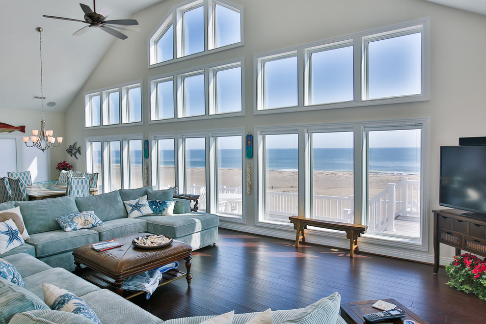 Photo of a large beach style open concept living room in Other with white walls, dark hardwood floors, a freestanding tv, no fireplace and brown floor.