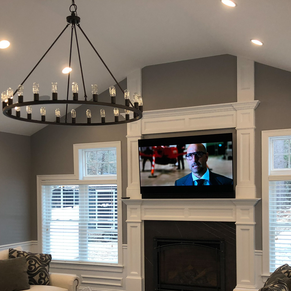 This is an example of a mid-sized transitional formal enclosed living room in Boston with grey walls, a standard fireplace, a stone fireplace surround and a wall-mounted tv.