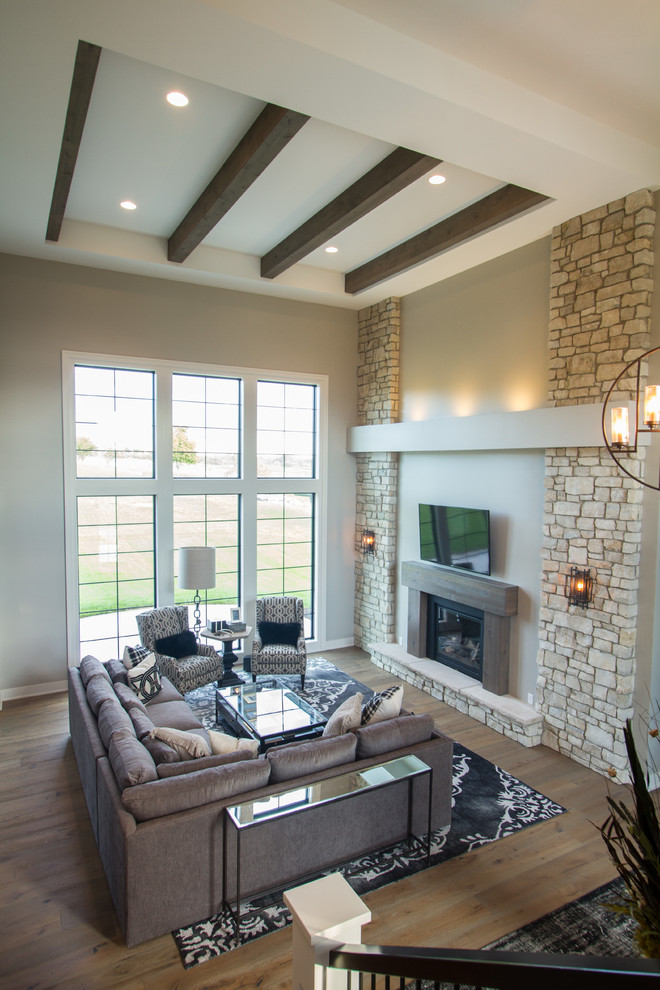 This is an example of an expansive traditional formal open concept living room in Omaha with beige walls, medium hardwood floors, a standard fireplace, a wood fireplace surround and a wall-mounted tv.