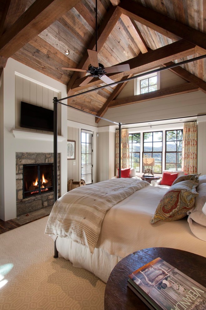 Bedroom - large rustic master dark wood floor and exposed beam bedroom idea with a standard fireplace, a stone fireplace and white walls