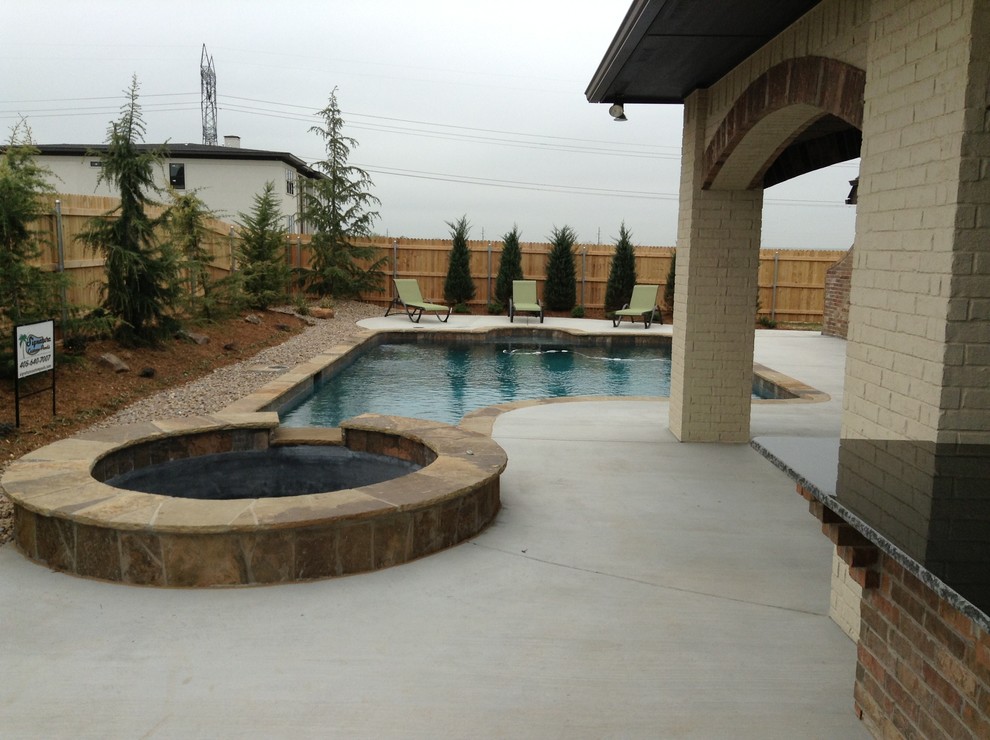 Design ideas for a small traditional backyard custom-shaped pool in Oklahoma City with a hot tub and concrete slab.