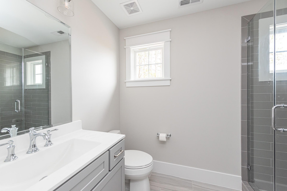 Réalisation d'une salle de bain tradition de taille moyenne avec un placard à porte shaker, des portes de placard grises, WC séparés, un carrelage gris, des carreaux de céramique, un mur gris, un sol en carrelage de céramique, un lavabo intégré, un plan de toilette en marbre, un sol gris, une cabine de douche à porte battante, un plan de toilette blanc, meuble simple vasque et meuble-lavabo encastré.