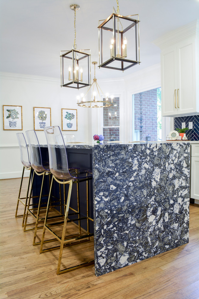 Example of a mid-sized transitional l-shaped medium tone wood floor and brown floor enclosed kitchen design with an undermount sink, flat-panel cabinets, white cabinets, quartz countertops, blue backsplash, porcelain backsplash, stainless steel appliances, an island and white countertops