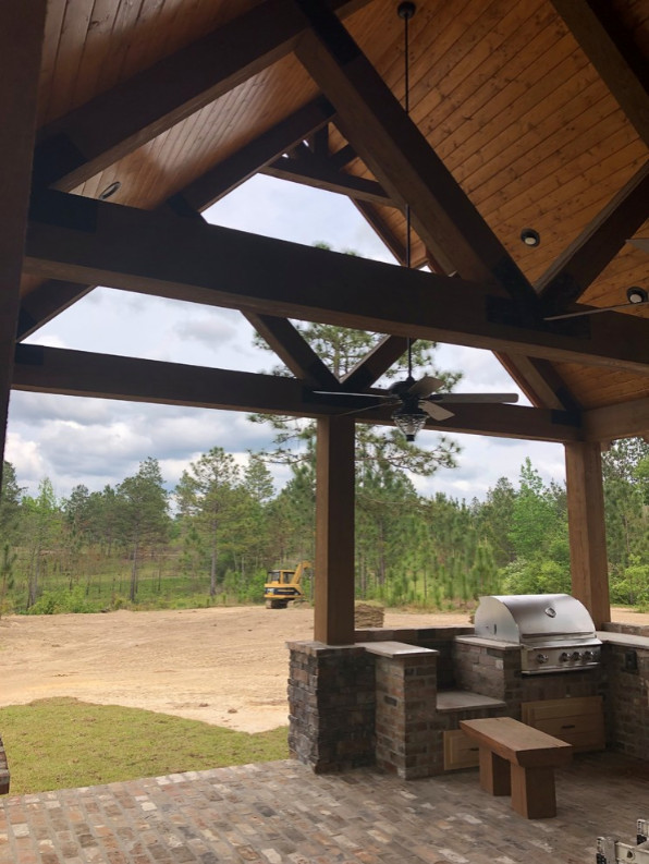 Large mountain style brick outdoor kitchen porch idea with a roof extension