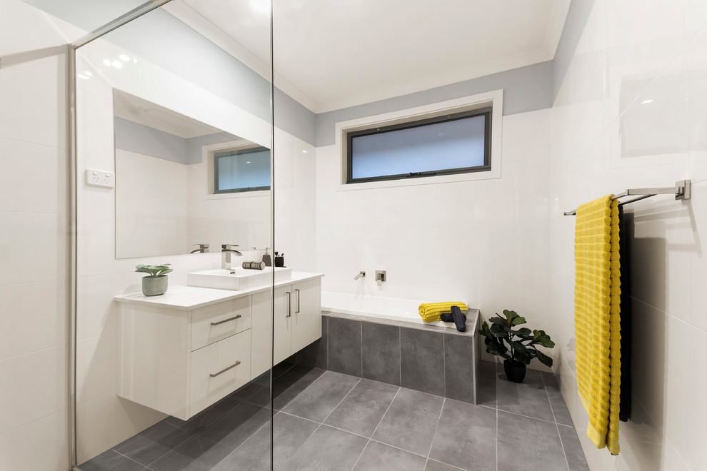 Design ideas for a contemporary bathroom in Melbourne with flat-panel cabinets, white cabinets, a drop-in tub, white walls, a vessel sink, grey floor and white benchtops.