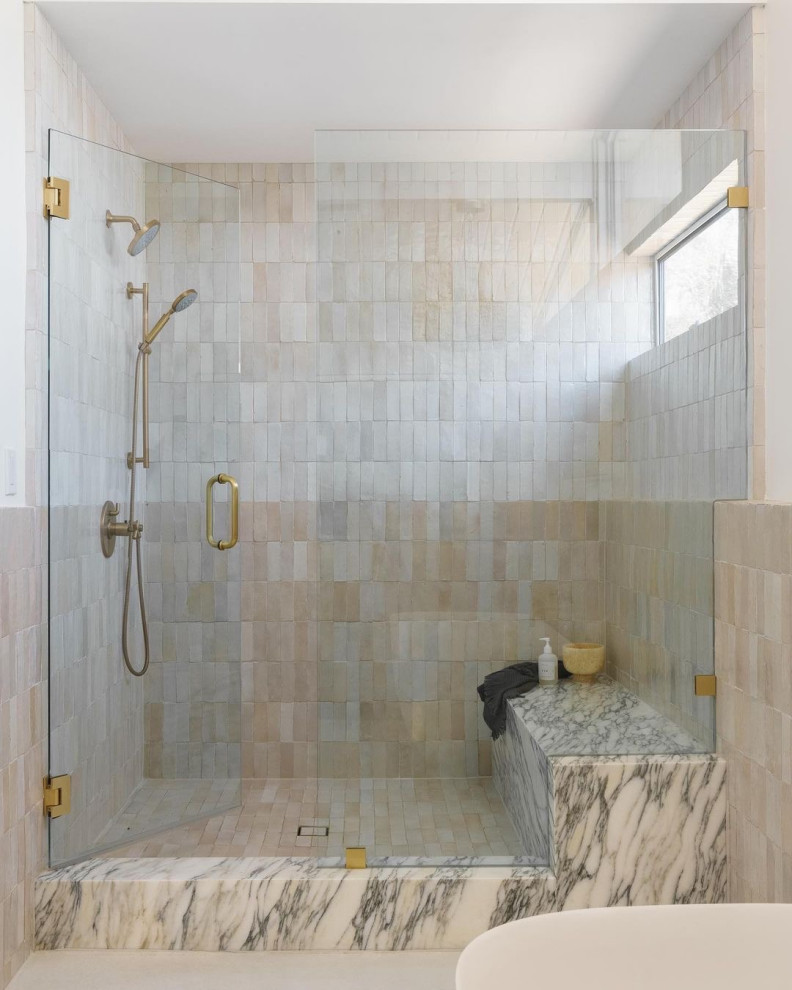 This is an example of a mid-sized midcentury master bathroom in Orange County with flat-panel cabinets, light wood cabinets, a freestanding tub, an open shower, a one-piece toilet, beige tile, ceramic tile, white walls, concrete floors, an undermount sink, marble benchtops, white floor, a hinged shower door, multi-coloured benchtops, a shower seat, a double vanity, a built-in vanity and vaulted.