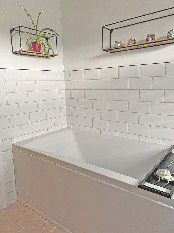 Photo of a mid-sized scandinavian bathroom in Sussex with grey cabinets, white tile, subway tile, a drop-in sink, a single vanity, an alcove tub, a one-piece toilet, white walls, ceramic floors, pink floor and a floating vanity.