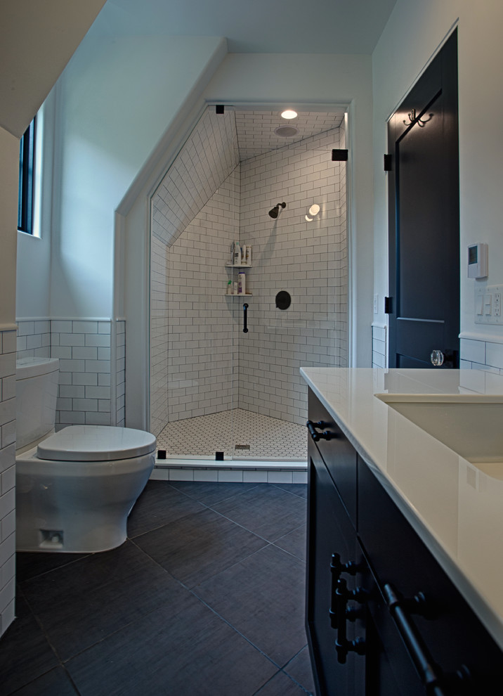 Photo of a large transitional master bathroom in New York with recessed-panel cabinets, dark wood cabinets, an alcove shower, a one-piece toilet, white tile, subway tile, white walls, limestone floors, an undermount sink, engineered quartz benchtops, black floor and a hinged shower door.