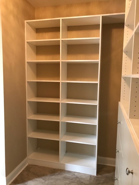 This is an example of a mid-sized traditional gender-neutral walk-in wardrobe in Other with flat-panel cabinets, white cabinets, linoleum floors and beige floor.