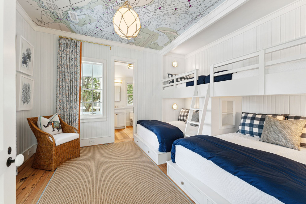 Foto på ett maritimt könsneutralt barnrum kombinerat med sovrum, med vita väggar och mellanmörkt trägolv