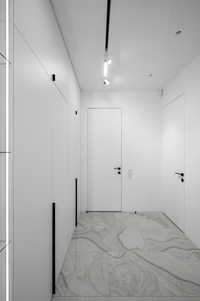 Diseño de armario vestidor unisex contemporáneo de tamaño medio con armarios con paneles lisos, puertas de armario blancas, suelo de baldosas de porcelana y suelo gris