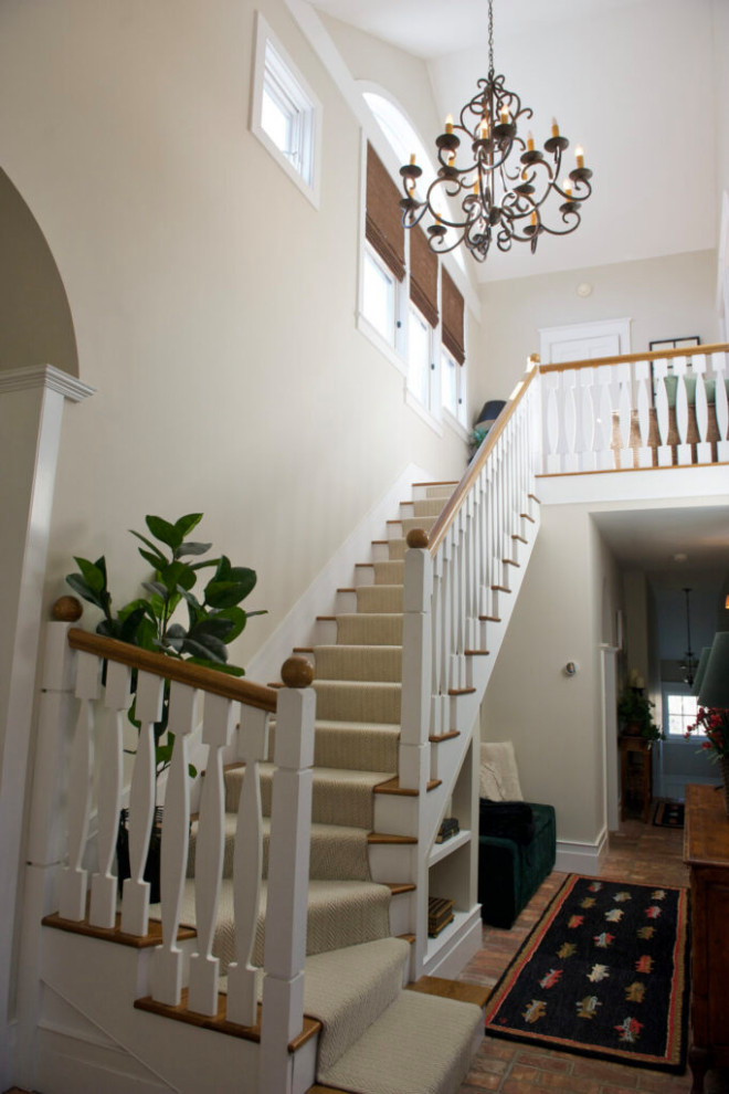 На фото: угловая деревянная лестница среднего размера в стиле неоклассика (современная классика) с ступенями с ковровым покрытием и деревянными перилами