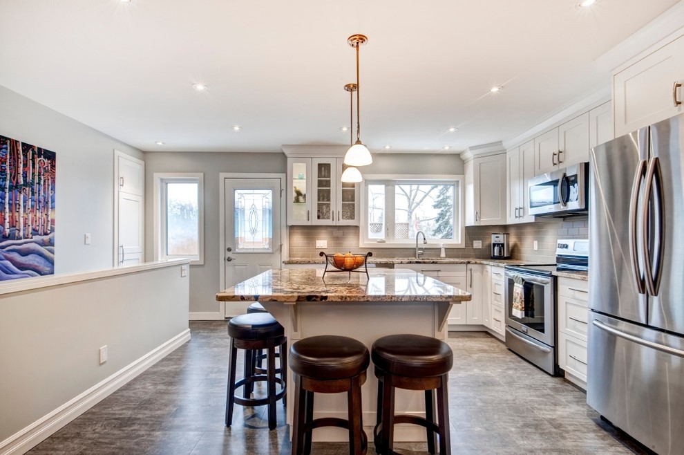 Eat-in kitchen - mid-sized transitional l-shaped vinyl floor eat-in kitchen idea in Calgary with an undermount sink, shaker cabinets, white cabinets, granite countertops, gray backsplash, subway tile backsplash, stainless steel appliances and an island