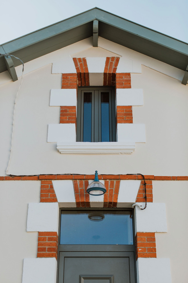 Inspiration pour une façade de maison de ville beige marine en brique à un étage avec un toit à deux pans et un toit en tuile.